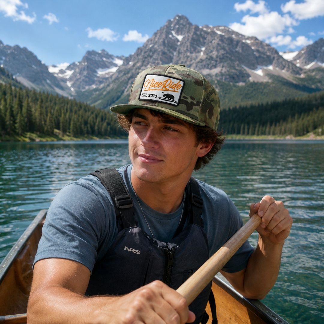 Green camo Niceride hat displayed on vibrant berries, showcasing outdoor style and brand identity.