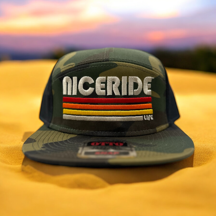 NICERIDE Otto 7 Panel Snapback Trucker Hat in Camo with colorful embroidered design and evening glow backdrop.