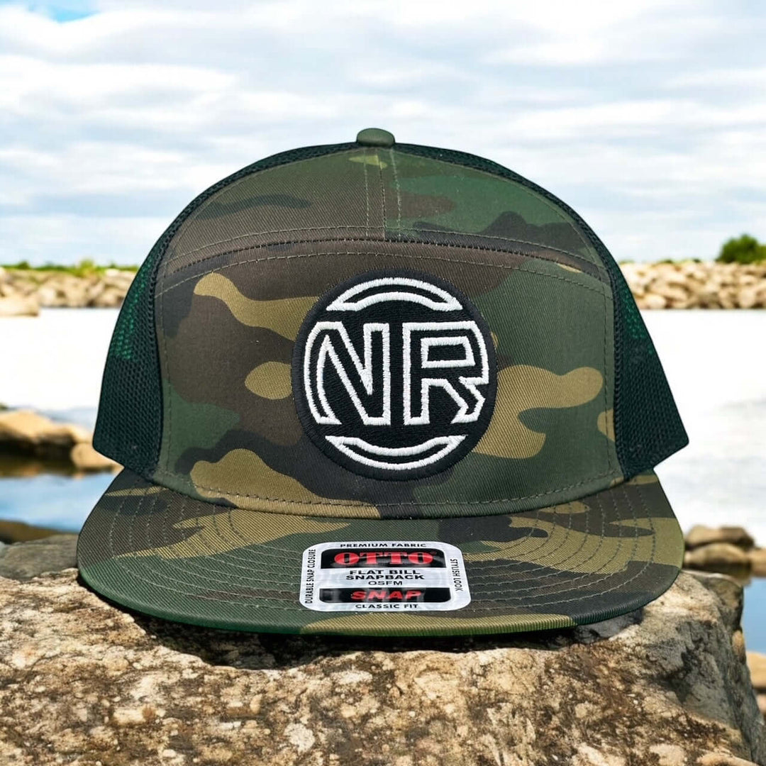 Inner Circle Unisex 7 Panel Trucker Hat featuring NR logo in camo design on rocky surface