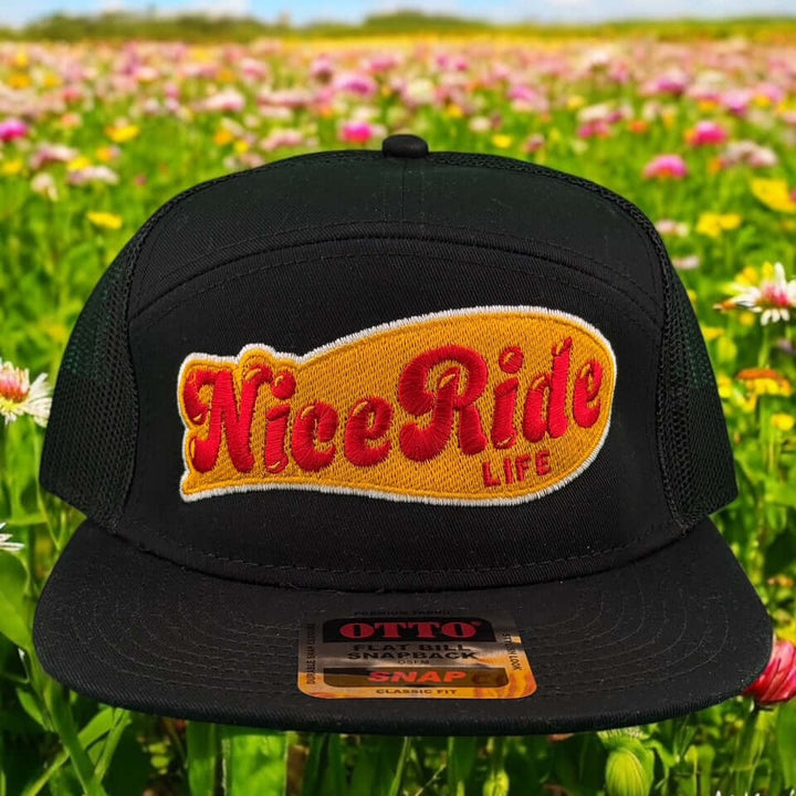NICERIDE My Fav Otto seven-panel snapback hat with vibrant embroidery on a black cap, set against a colorful flower field.