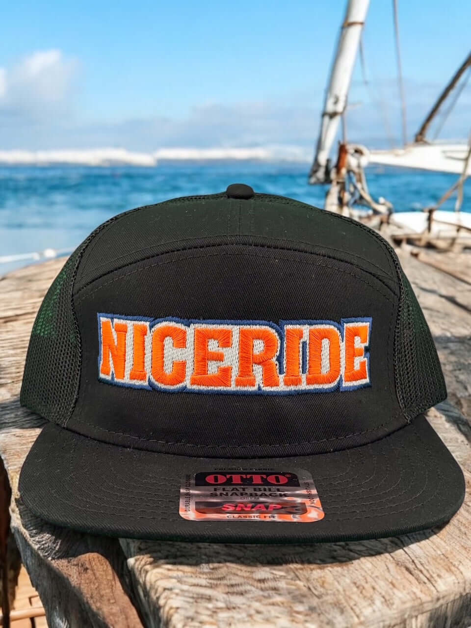 NICERIDE Friday Otto seven-panel snapback hat displayed against a scenic beach background.