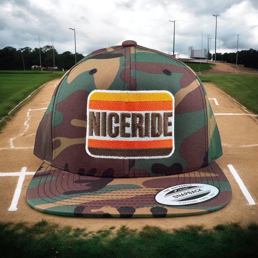 NICERIDE unisex adjustable trucker hat in camouflage with embroidered logo on a baseball field background.