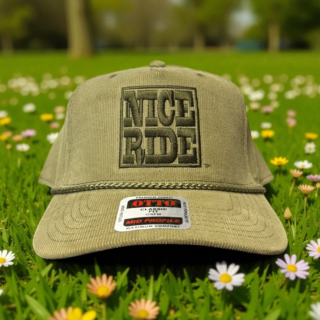 NR Trucker Corduroy OTTO CAP 5 Panel Snapback Baseball Cap on grass surrounded by flowers.
