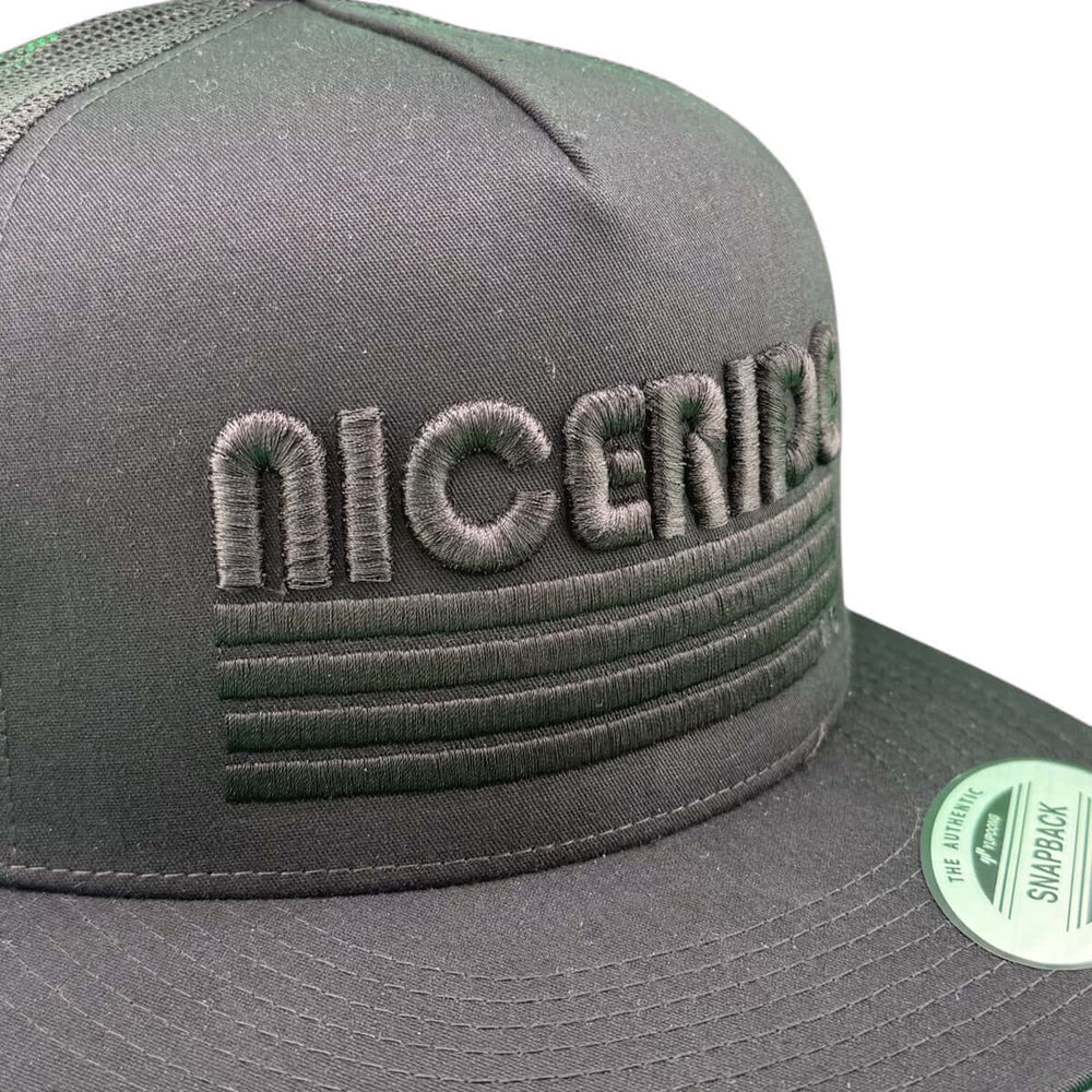 Close-up of NICERIDE's black puff trucker hat showcasing embroidered design on sleek black fabric.