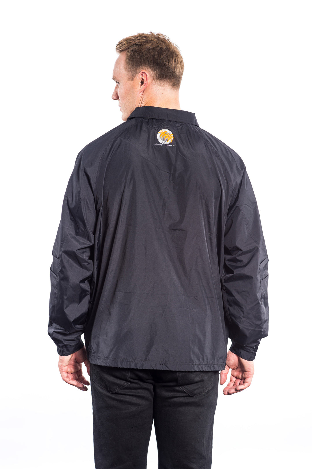 Back view of a man wearing a Coach Windbreaker Jacket with an embroidered patch.