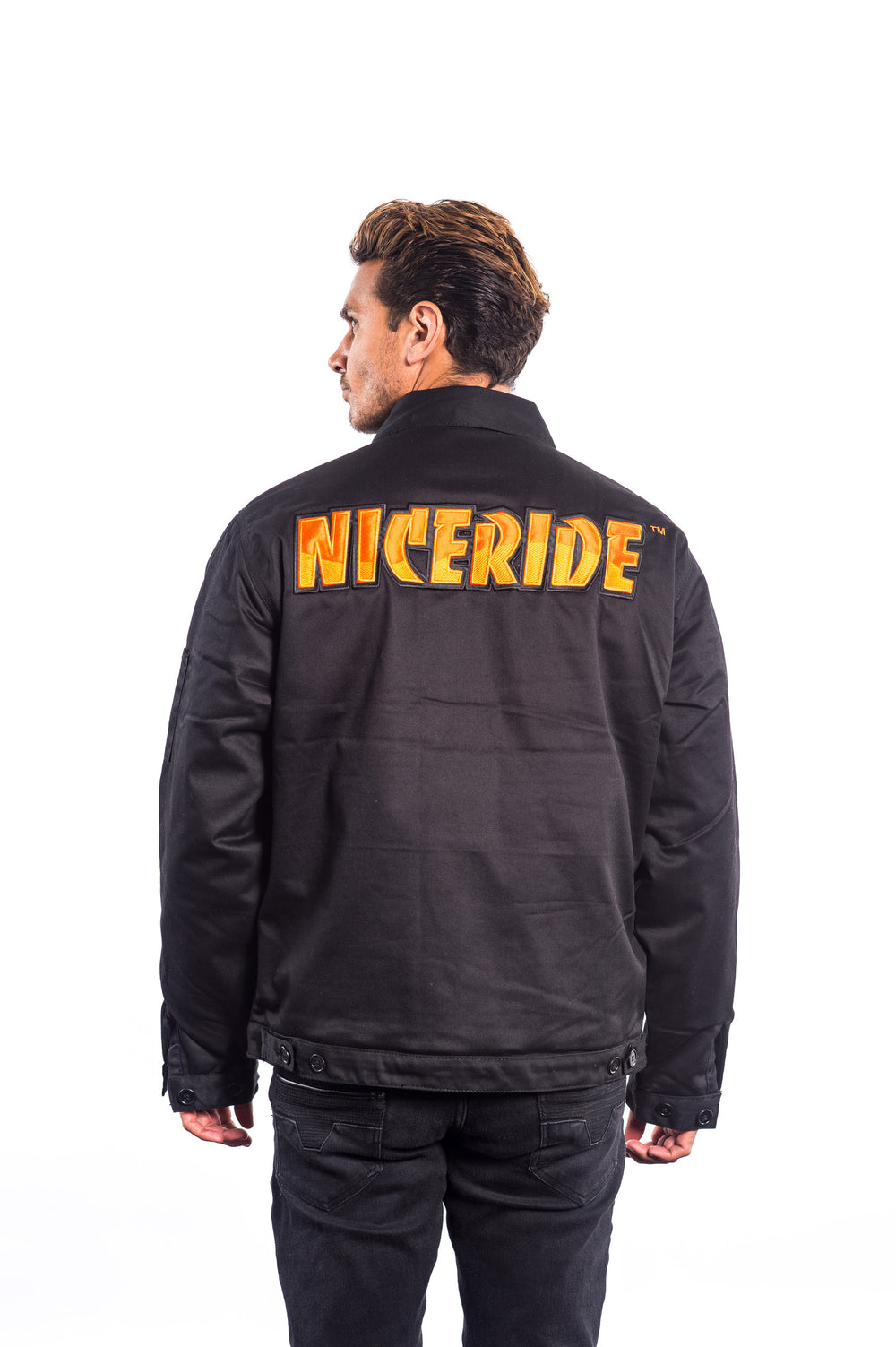 Man wearing a black canvas jacket with NICERIDE embroidered on the back and left chest.