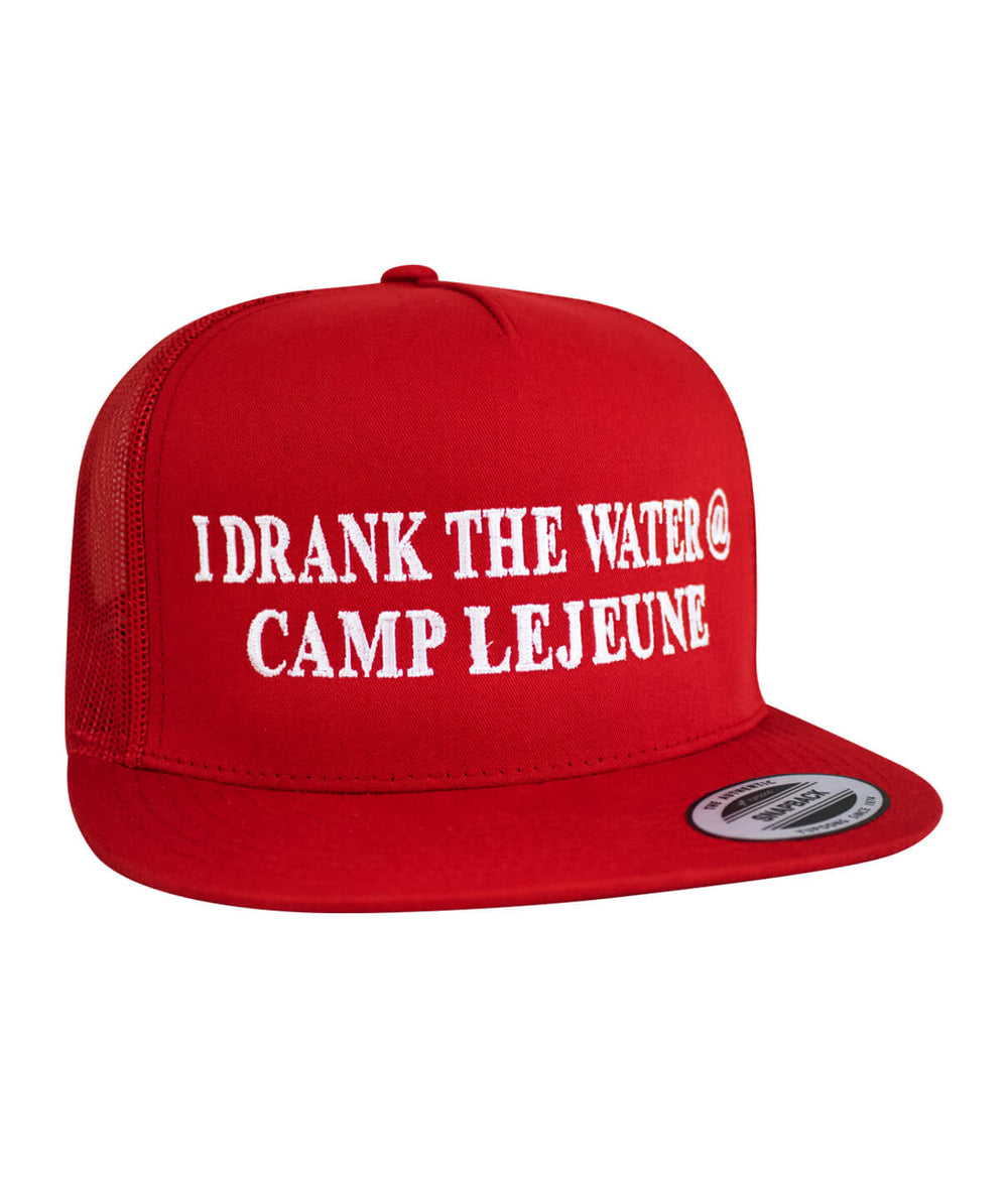 Trucker hat in red featuring 'I Drank the Water @ Camp Lejeune' embroidered on the front.
