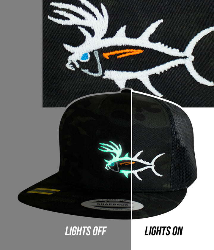 Close-up of Buck-Eye LP snapback hat showing embroidered fish design, glowing in the dark with lights on.