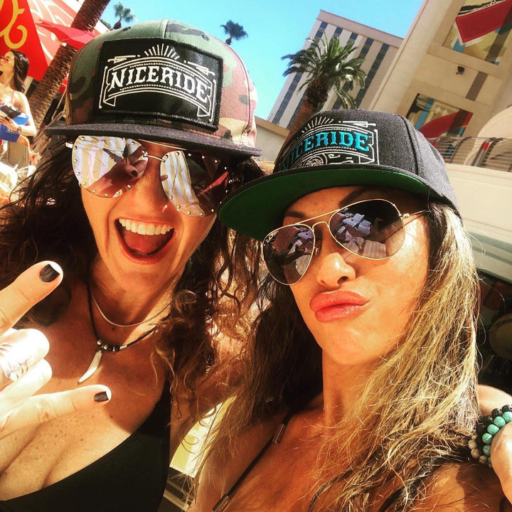 Two women wearing NICERIDE snapback hats, enjoying a sunny day by the pool, showcasing stylish summer vibes with their hats.