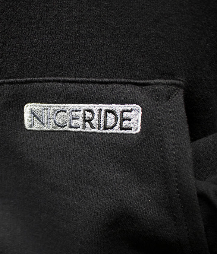 Close-up of NICERIDE logo embroidered on a black pullover hoodie, showcasing quality and style.