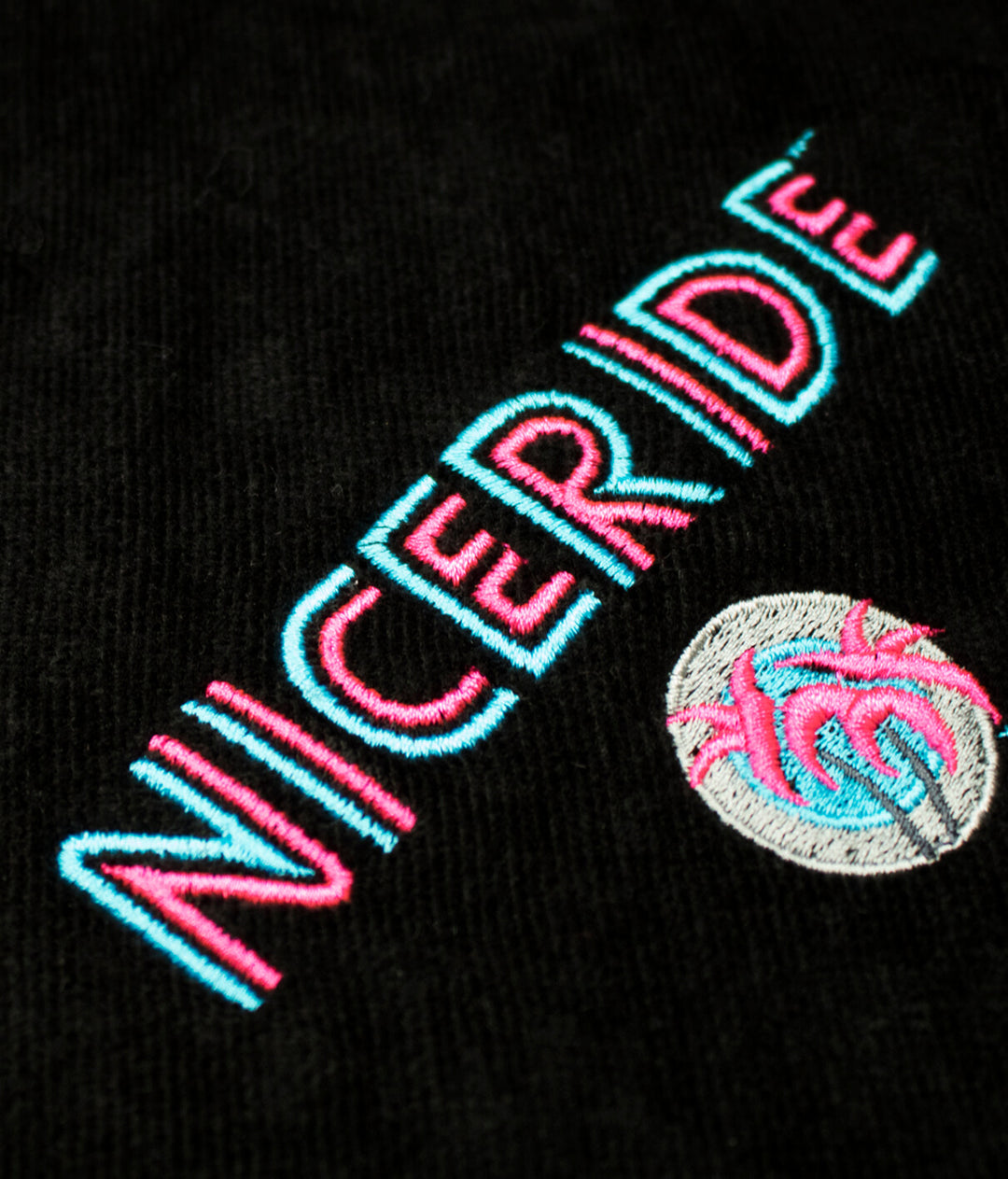 NICERIDE logo embroidery on a black towel, showcasing vibrant colors and detailed design on soft terry fabric.