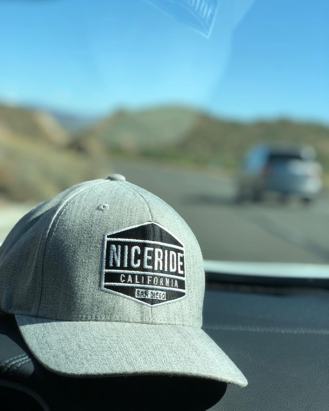 Good Times Snapback hat with NICERIDE California logo displayed on dashboard against scenic background.