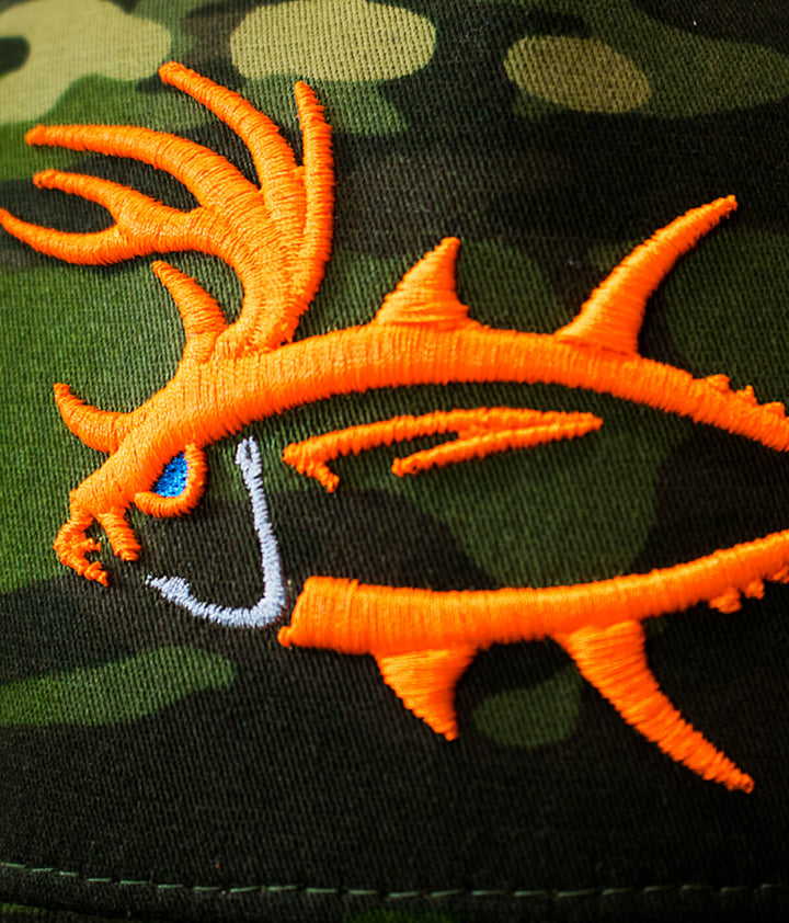 Close-up of Buck-Eye 3-D unisex snapback trucker hat with embroidered fish design on a camo background.