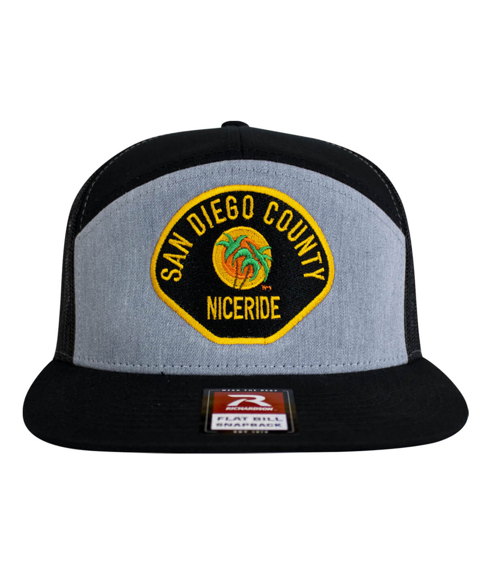 The Badge 7 Panel Trucker Hat featuring San Diego County NICERIDE embroidered design.