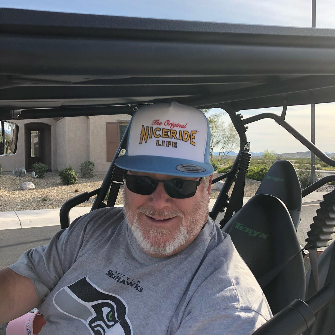 Person wearing a trucker hat with NICERIDE design, showcasing the Empty Forest hat style in a vehicle setting.