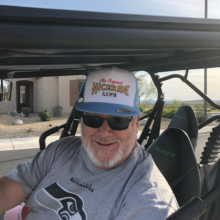 Person wearing a trucker hat with NICERIDE design, showcasing the Empty Forest hat style in a vehicle setting.