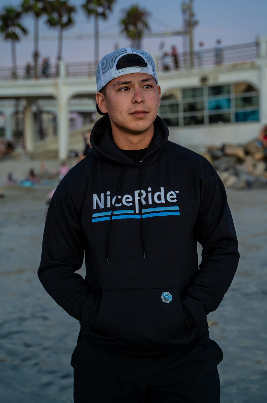 Man wearing a black pullover hoodie with NiceRide design at the beach, focused on comfort and style for adults and teens.