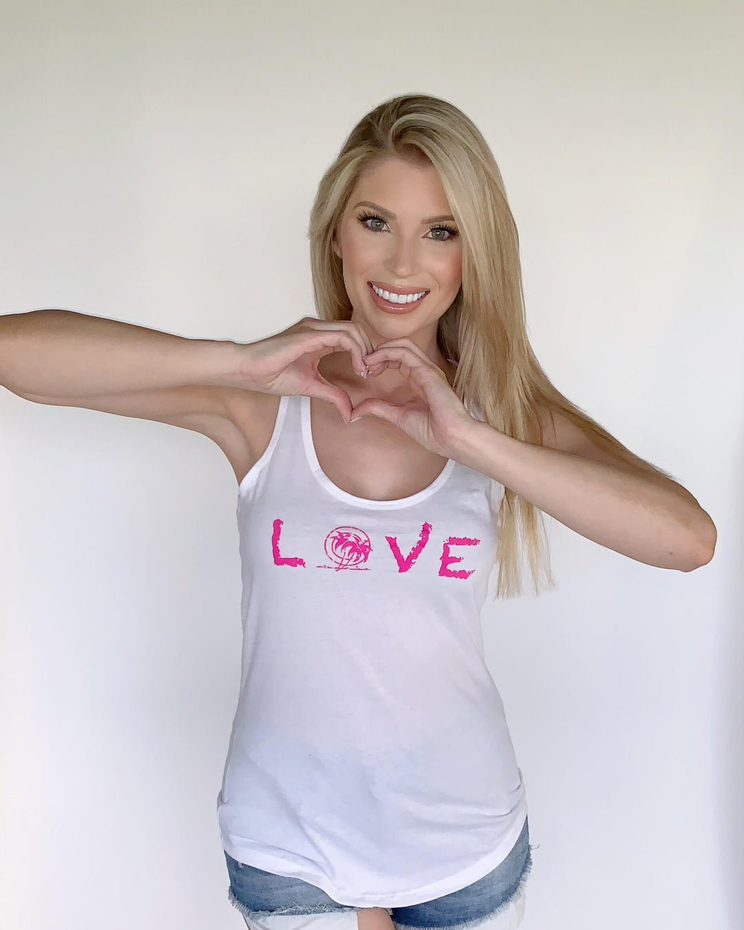 Woman in Palm Beach tank top forming a heart shape with hands, featuring &