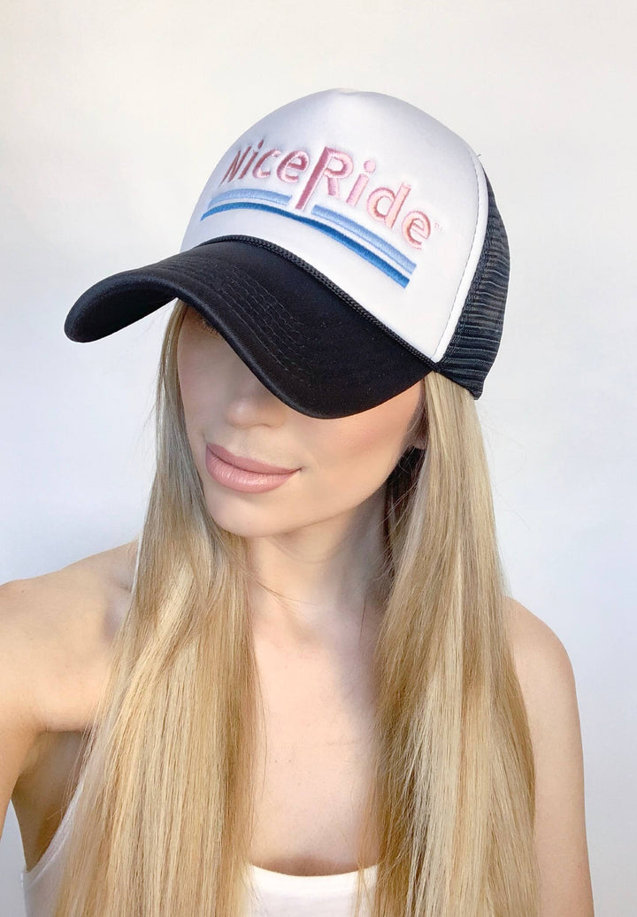 Female model wearing a foam trucker hat with "Nice Ride" embroidered on the front.