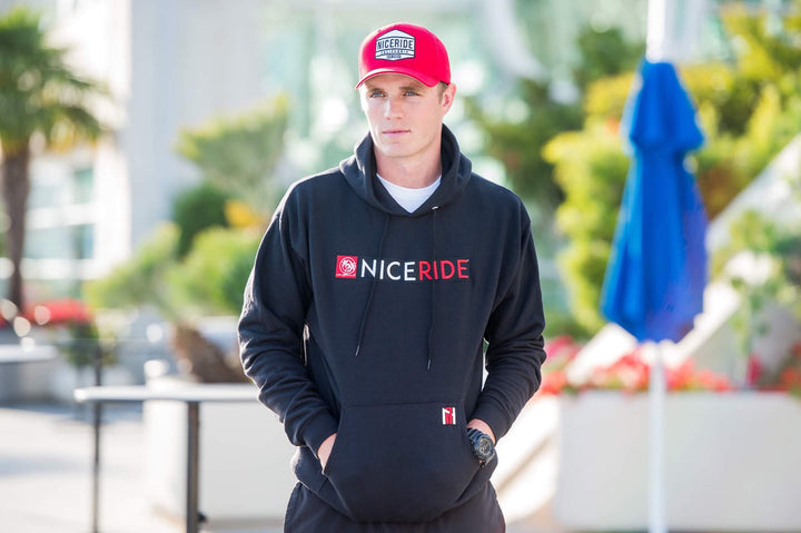 Black pullover hoodie featuring NICERIDE design, perfect hoodie for men and women, worn outdoors.