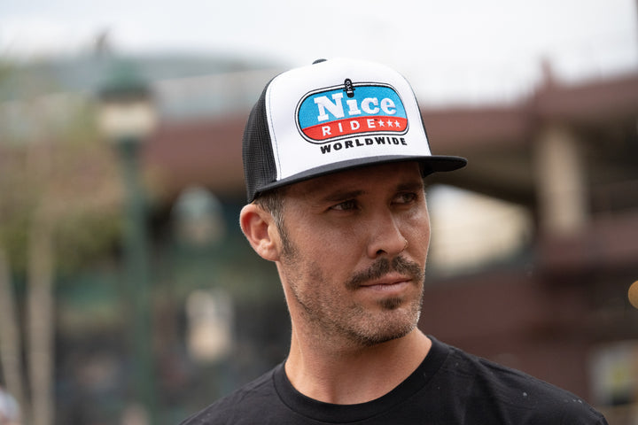 Man wearing a black and white trucker cap featuring NICERIDE&